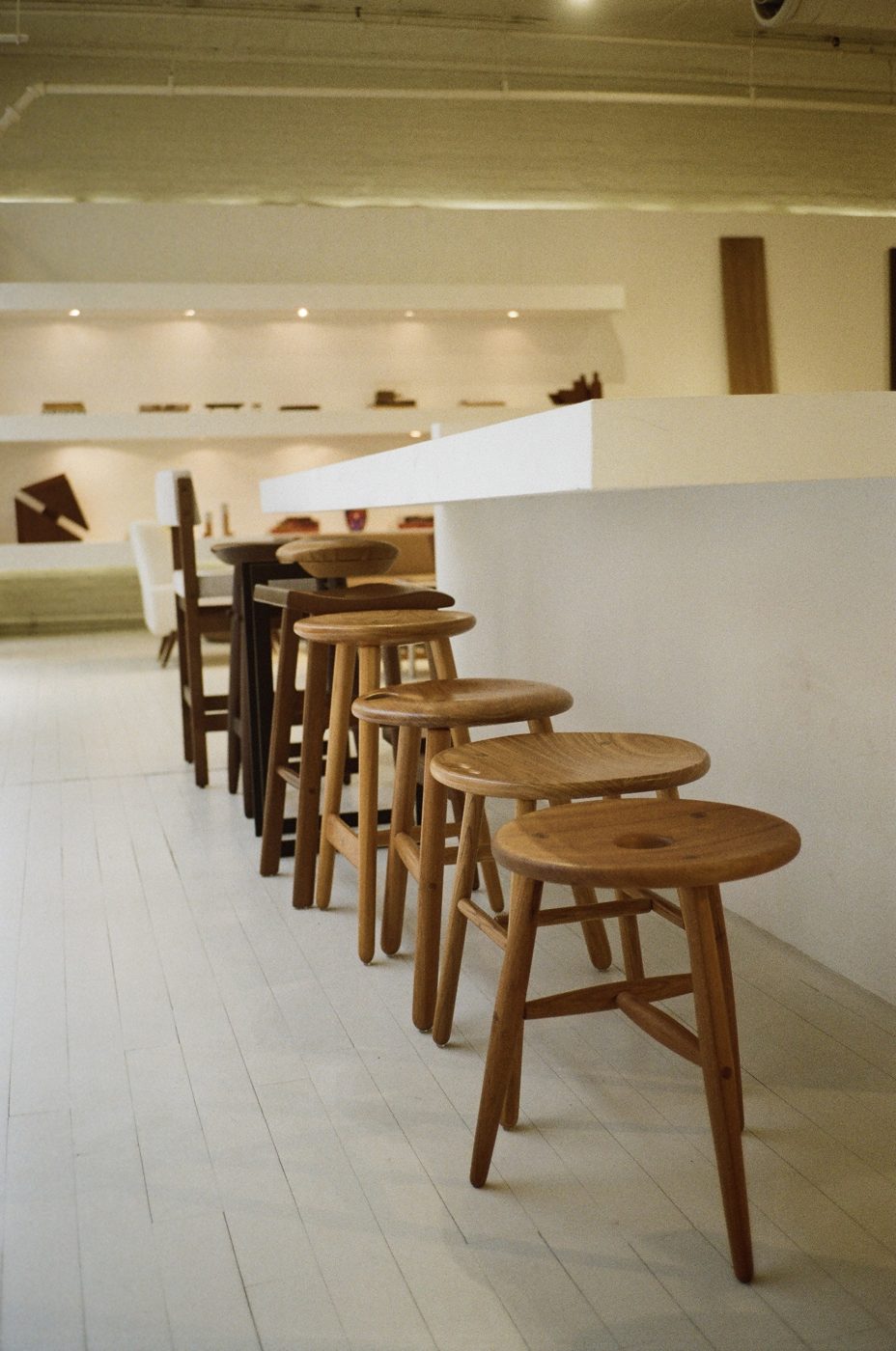 Row of carved wood stools along a white counter in the Espasso showroom