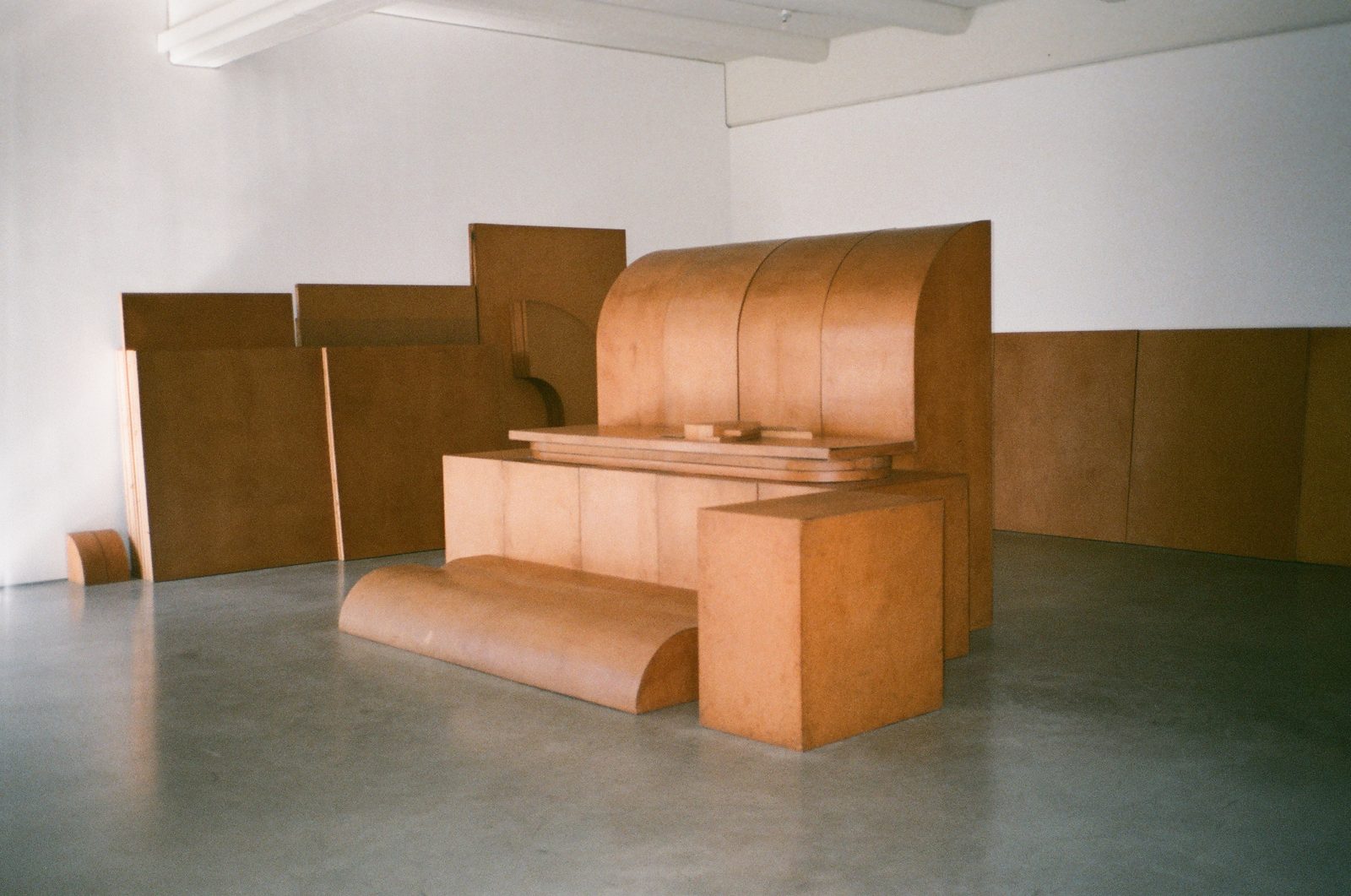 Large curved wooden installation in a bare white room